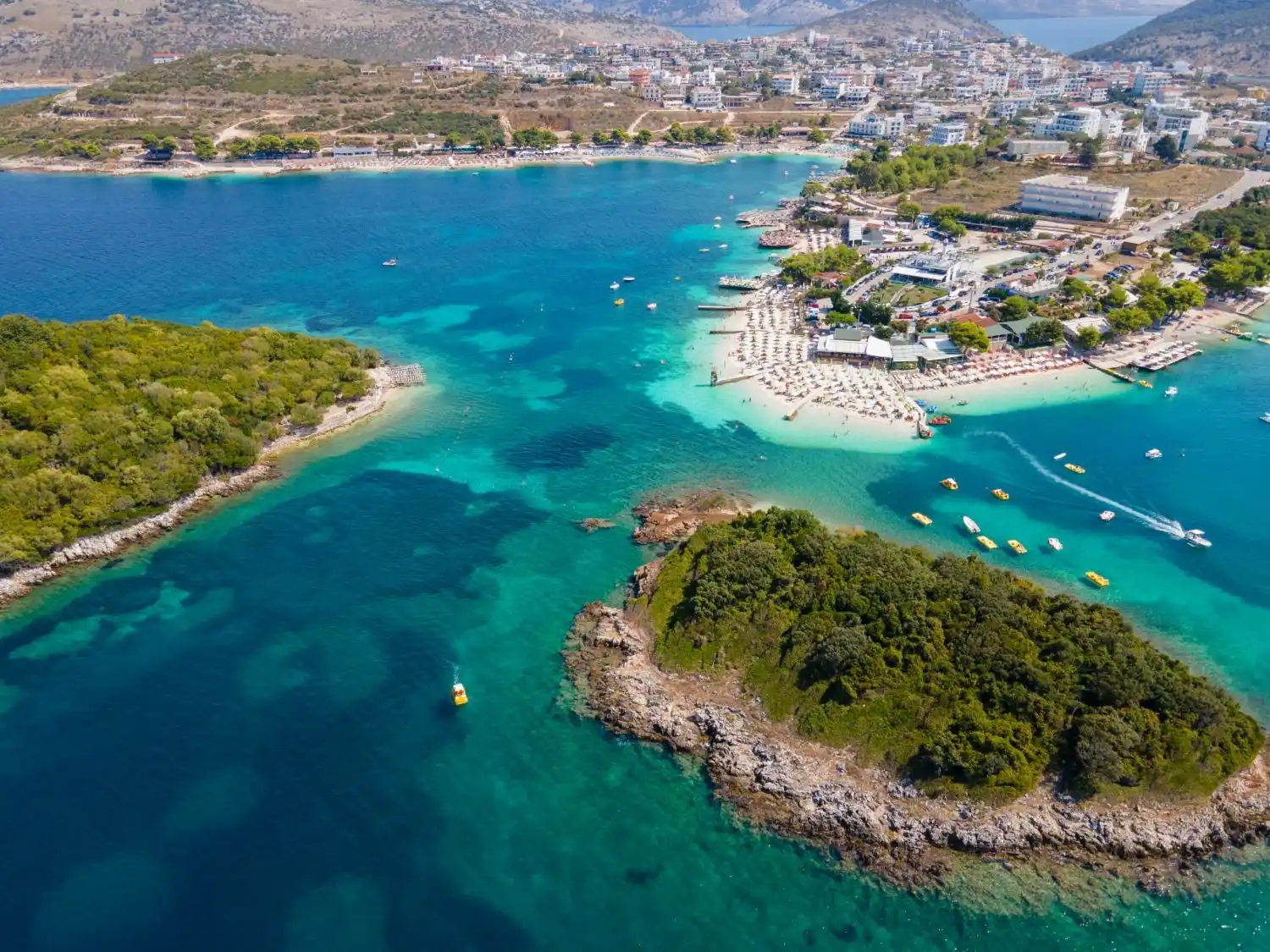 Aerial view of the Ksamil islands and beaches, with shallow turquoise water and pedal boats, south of Saranda