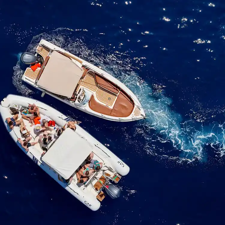 Aerial view of two boats on a sunny boat trip along the coast near Saranda, with passengers relaxing on deck